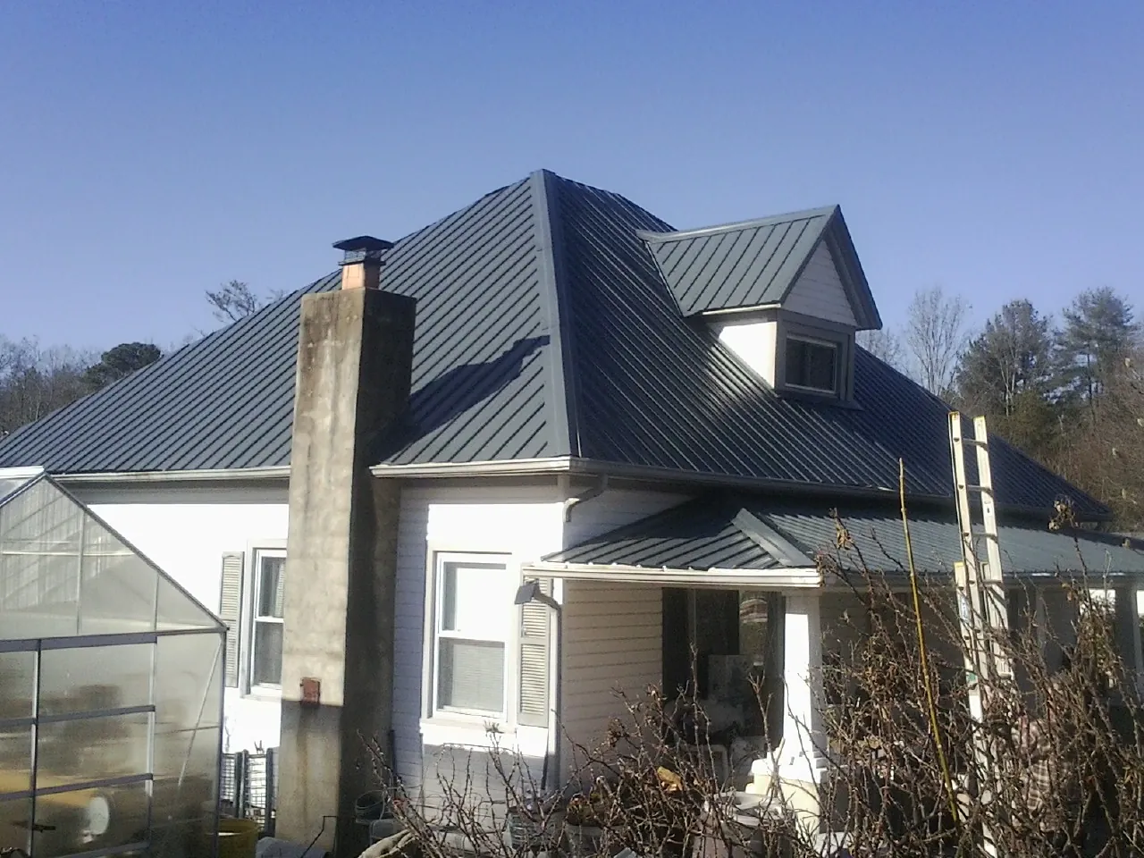 Dark blue standing seam metal roof on a white farmhouse with dormer — Slate & Tile Roof Repair by Roofing Brothers in Marstons Mills