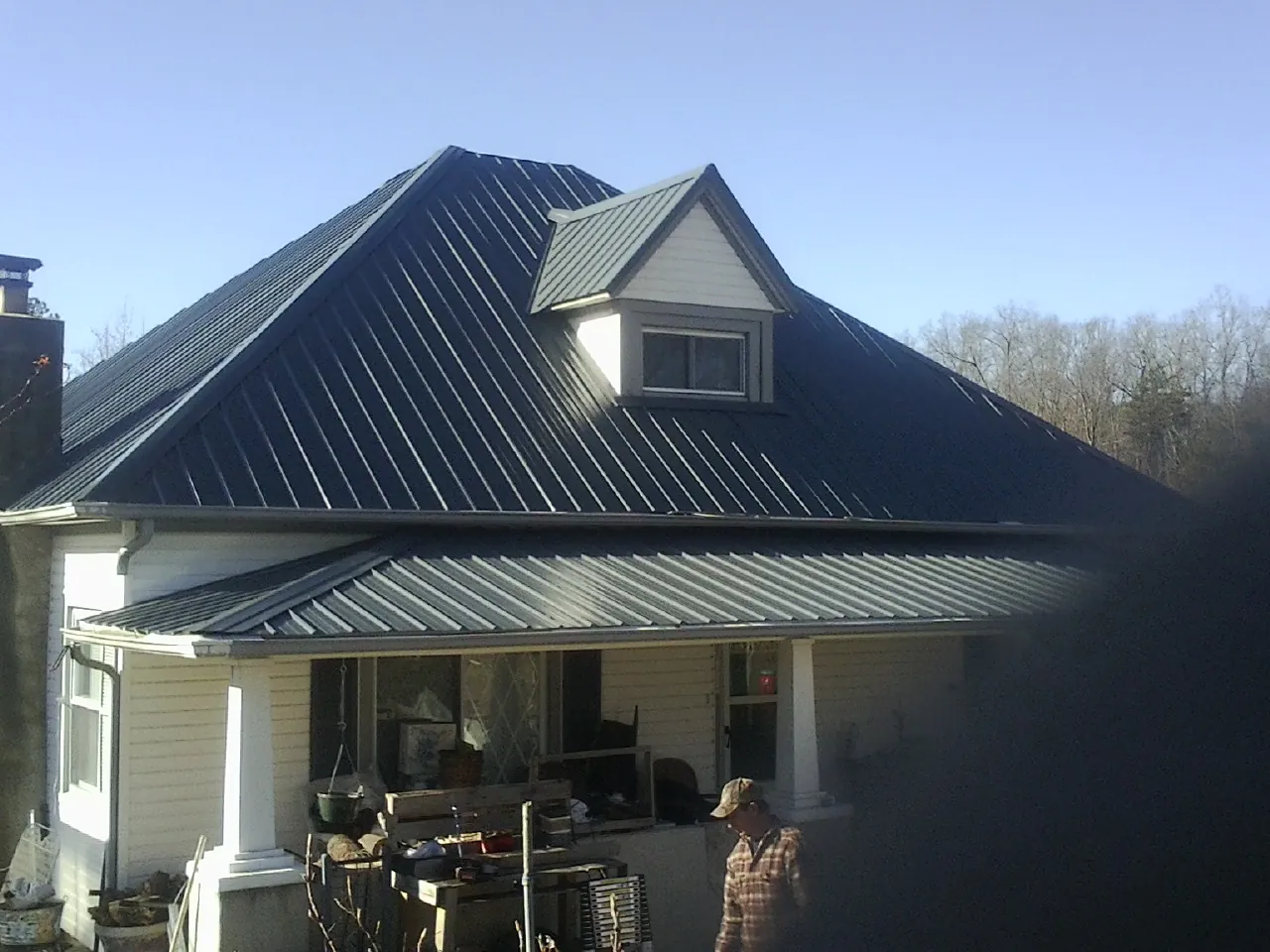 Dark blue standing seam metal roof with a dormer above a front porch in Marstons Mills