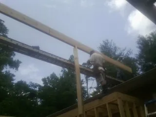 Carpenter setting a ridge beam over a new addition frame — Ice Dam Removal by Roofing Brothers in Marstons Mills