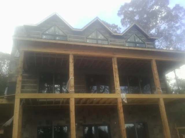 Dormers and porch framing on a large log home under construction — Roof Coating work by our crew in Marstons Mills