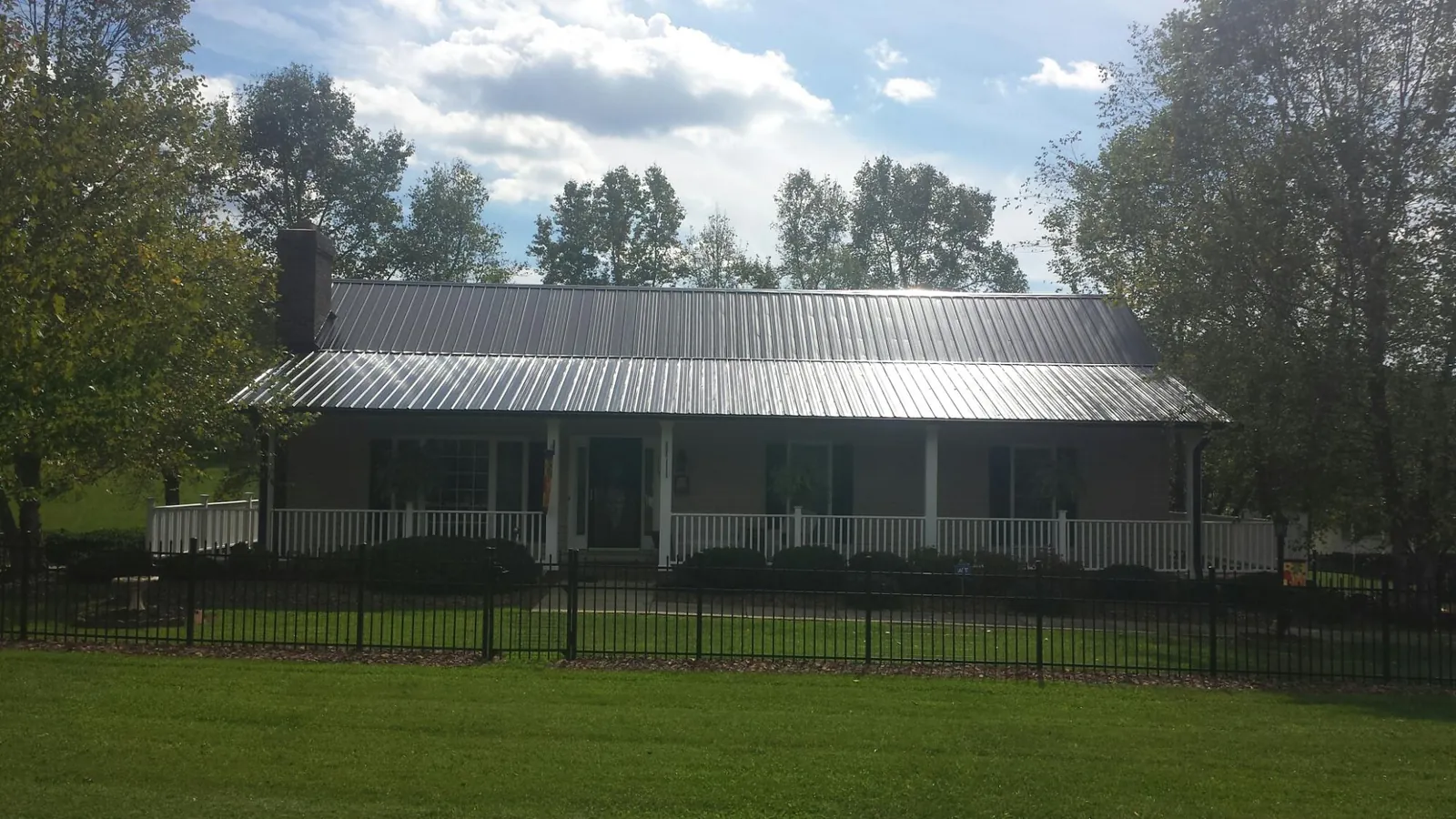 Gray metal roof on a brick ranch with a full width front porch — Gutter Guard Installation work by our crew in Marstons Mills