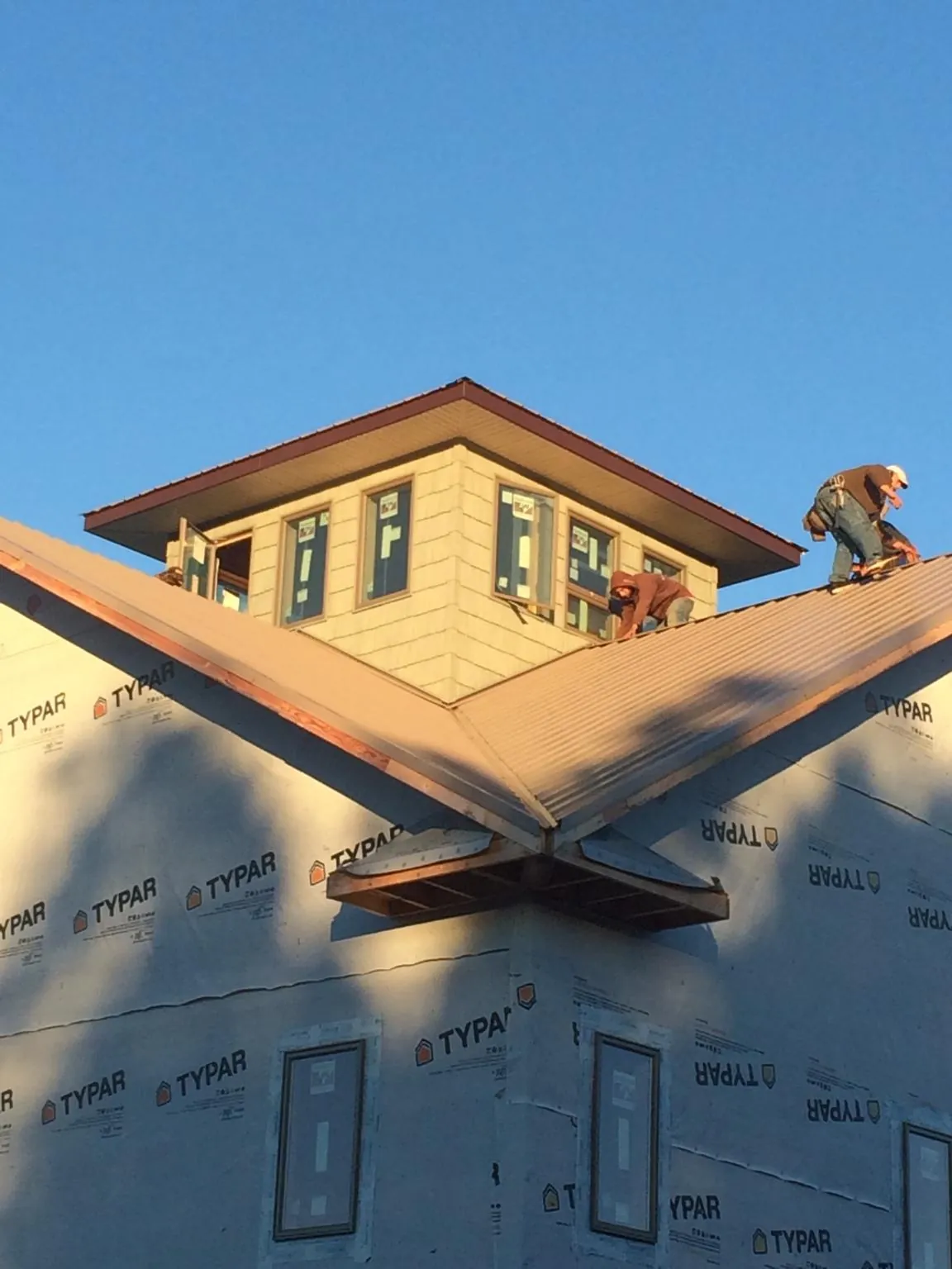Roofers working around a rooftop cupola on a new metal roof at sunset — Roof Waterproofing in Marstons Mills by Roofing Brothers